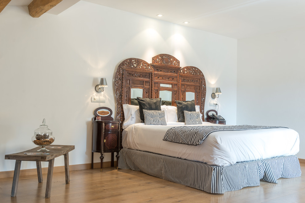 Foto di una camera matrimoniale mediterranea di medie dimensioni con pareti bianche, pavimento in legno massello medio e nessun camino