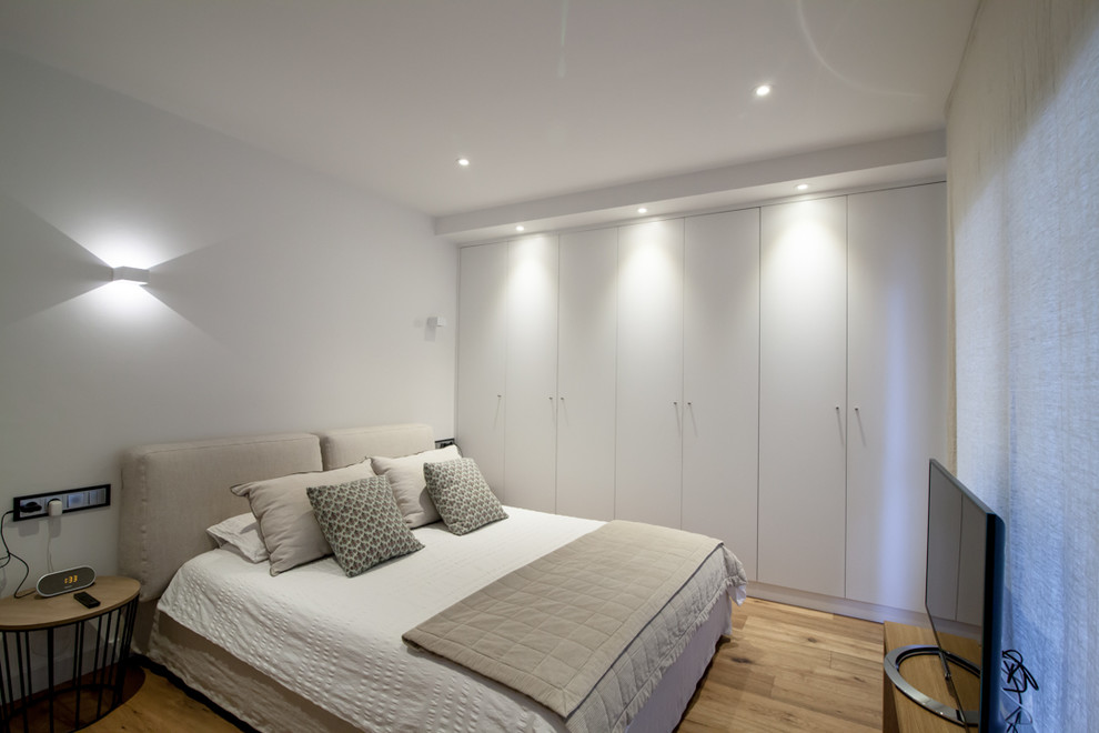 Mittelgroßes Klassisches Hauptschlafzimmer ohne Kamin mit weißer Wandfarbe und braunem Holzboden in Barcelona