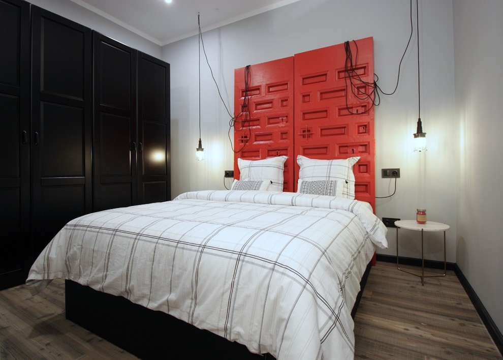 Foto de dormitorio industrial con paredes grises, suelo de madera oscura y suelo marrón