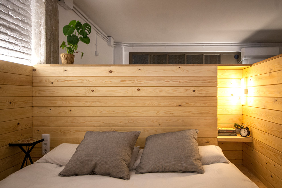 Ejemplo de dormitorio principal industrial pequeño con paredes blancas, suelo de madera clara y suelo marrón