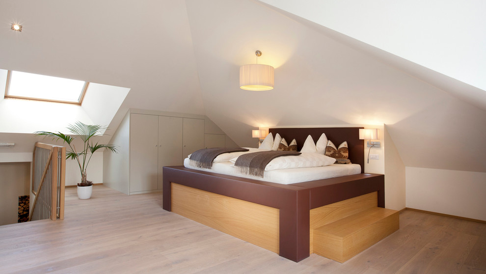 This is an example of a large contemporary master bedroom in Barcelona with white walls and medium hardwood flooring.