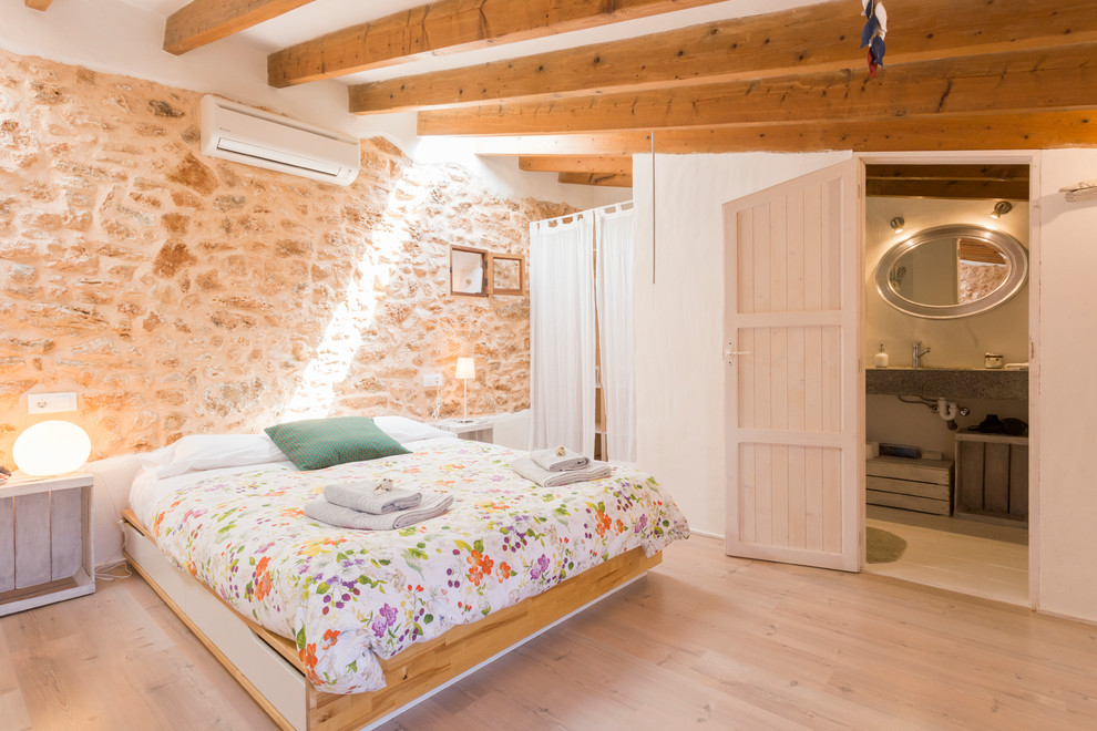 Diseño de dormitorio tipo loft rústico grande sin chimenea con paredes beige y suelo de madera clara