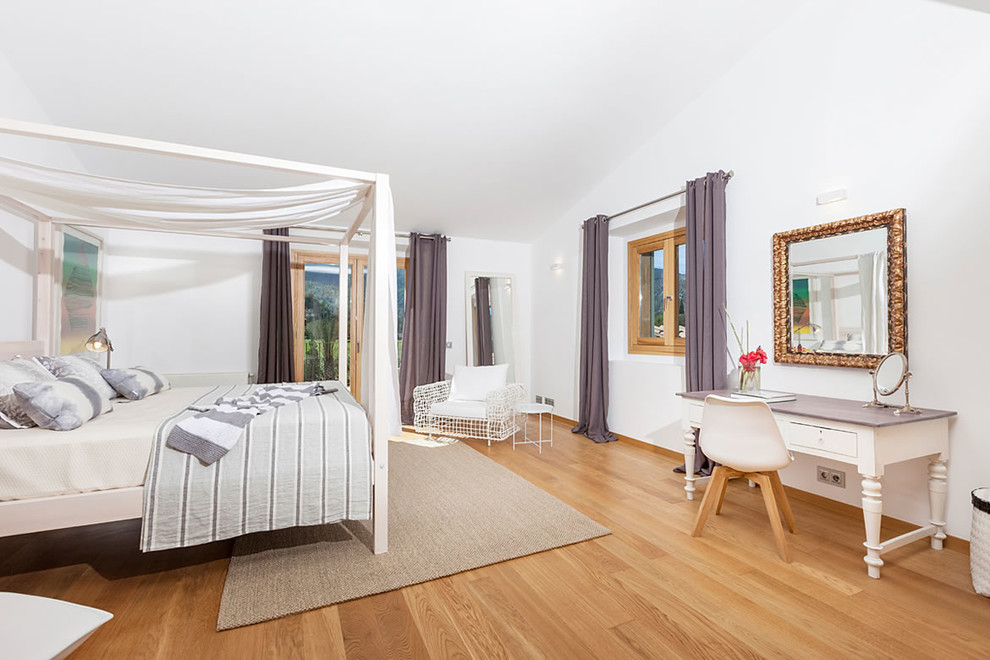 Modelo de dormitorio principal bohemio grande sin chimenea con paredes blancas y suelo de madera en tonos medios