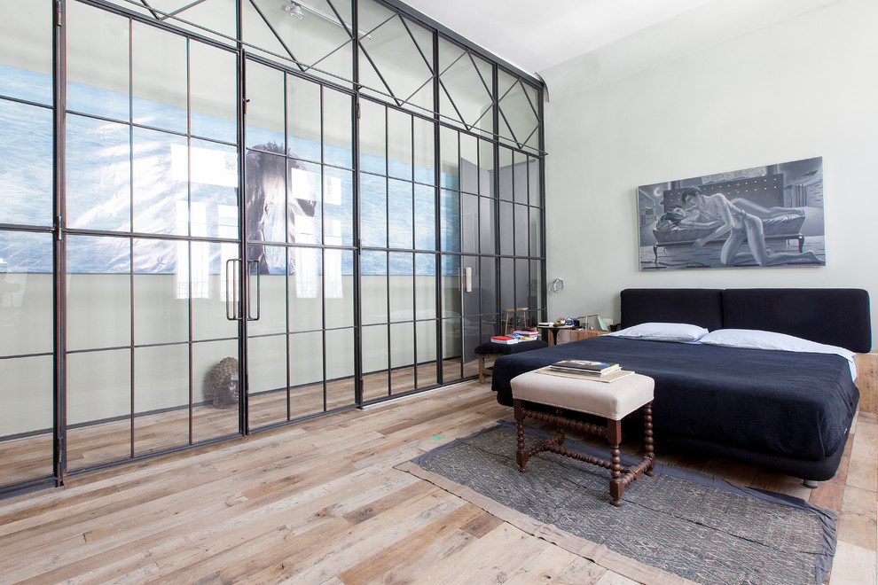 Foto de dormitorio principal urbano de tamaño medio sin chimenea con paredes blancas y suelo de madera clara