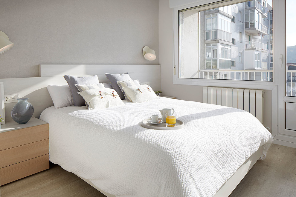 Modelo de dormitorio principal nórdico de tamaño medio sin chimenea con paredes grises, suelo beige y suelo laminado
