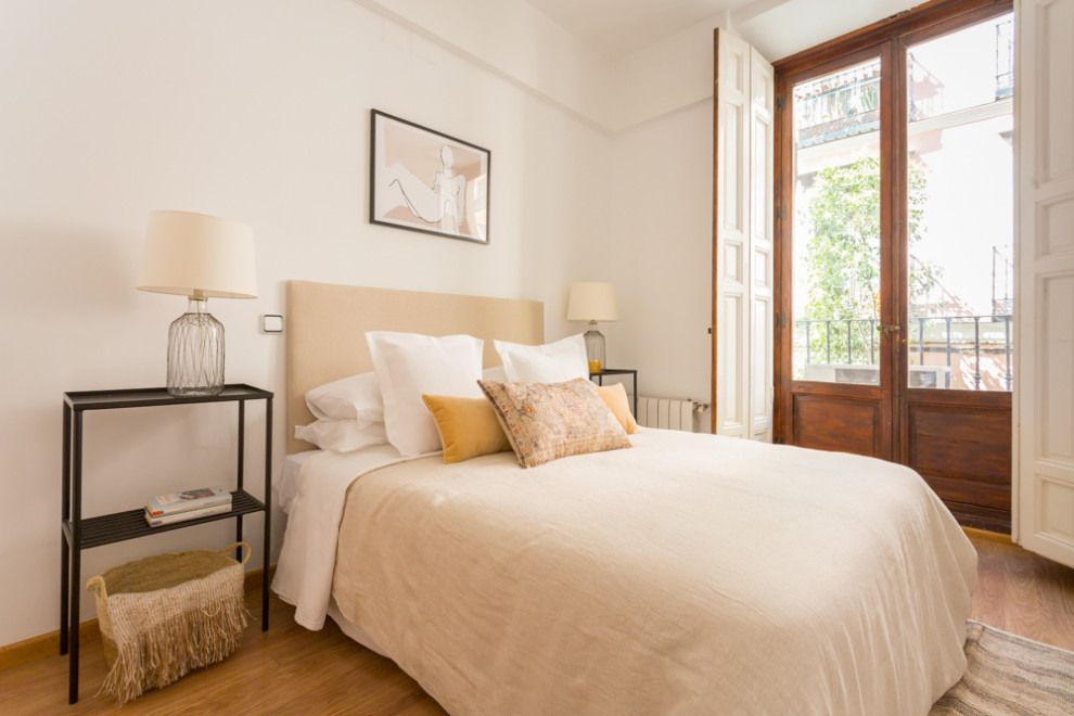 Photo of a mediterranean bedroom in Madrid with white walls, medium hardwood flooring and brown floors.