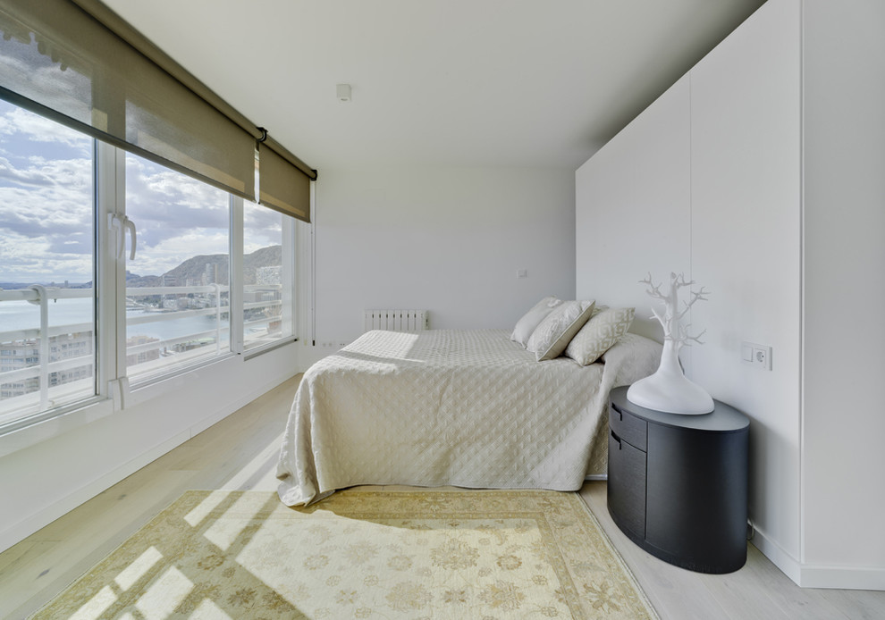 Diseño de dormitorio principal marinero de tamaño medio sin chimenea con paredes blancas y suelo de madera clara
