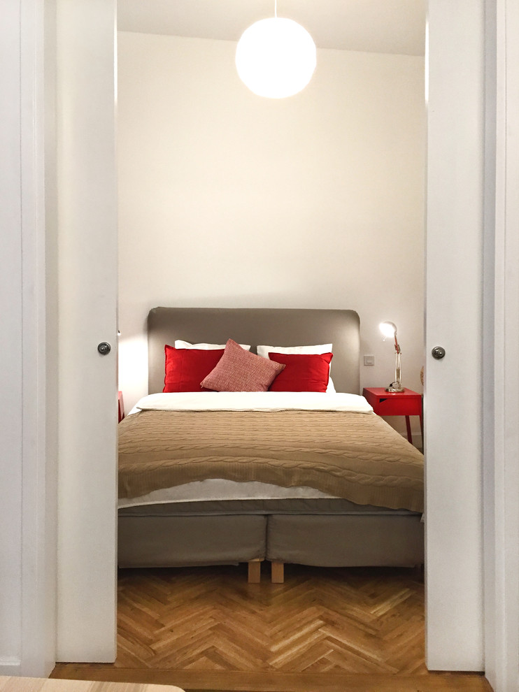 Cette image montre une petite chambre parentale design avec un mur blanc et un sol en bois brun.