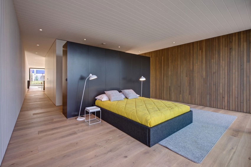 Diseño de dormitorio principal moderno grande sin chimenea con paredes marrones y suelo de madera clara
