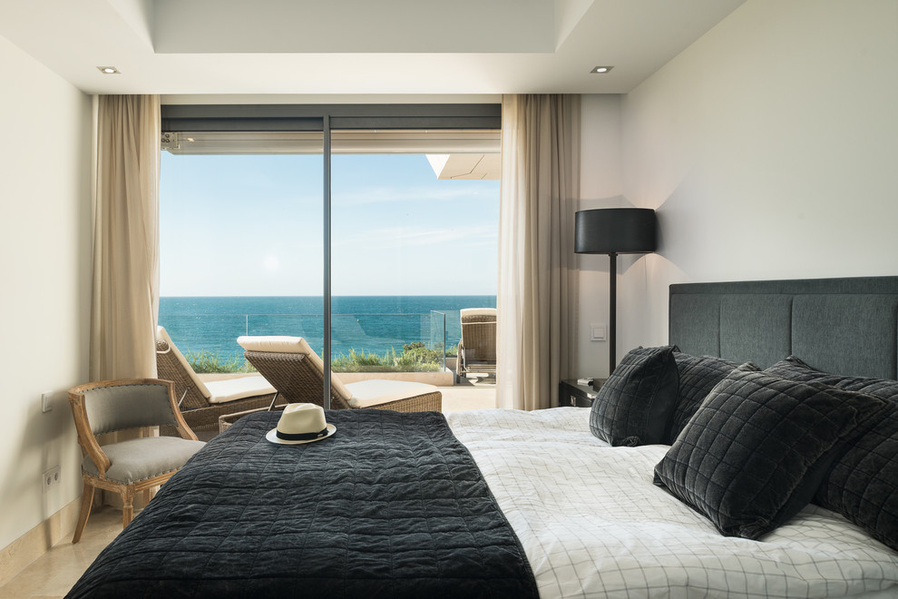 Imagen de dormitorio costero de tamaño medio sin chimenea con paredes blancas y suelo beige
