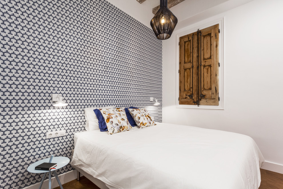 This is an example of a small contemporary master bedroom in Barcelona with multi-coloured walls, light hardwood flooring and a feature wall.