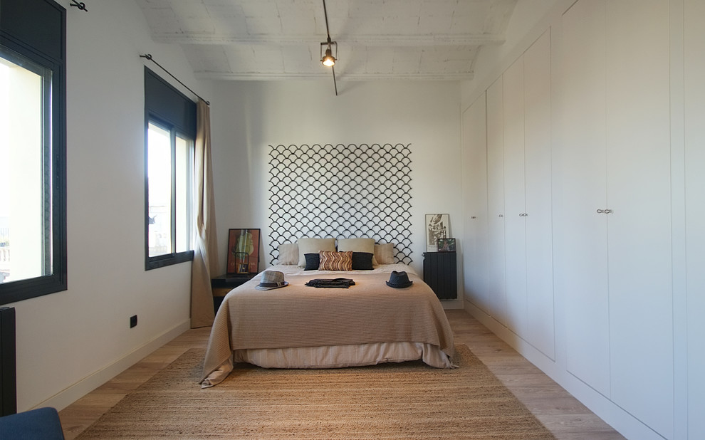 Cette image montre une chambre parentale design de taille moyenne avec un mur blanc, parquet clair et aucune cheminée.