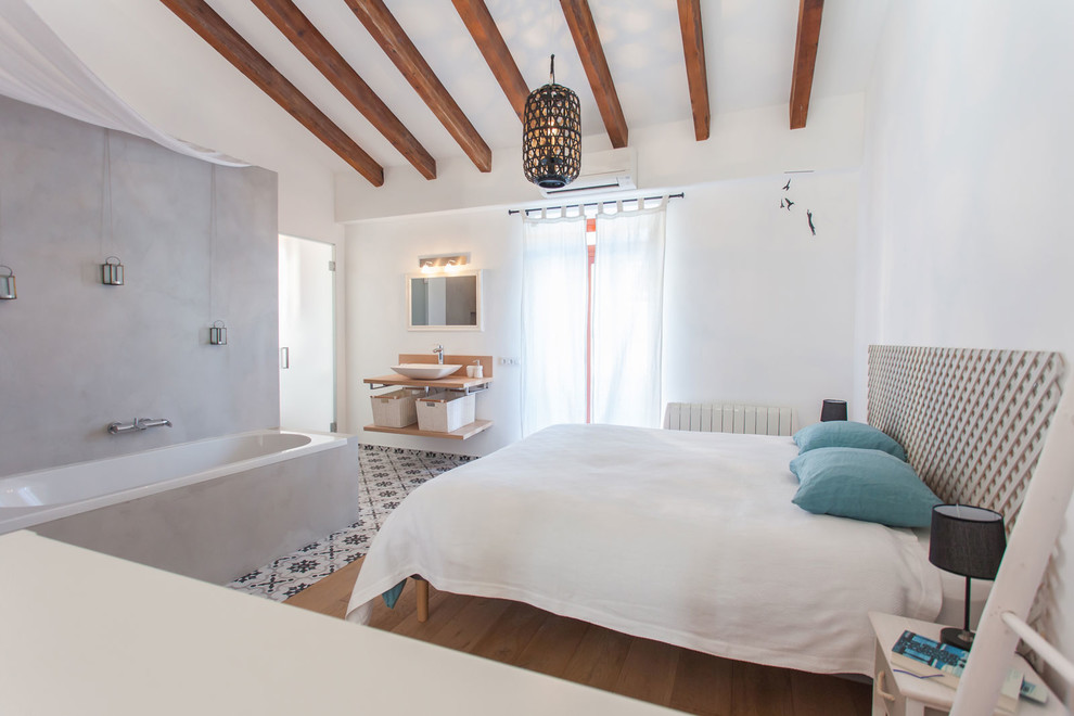 Immagine di una camera matrimoniale mediterranea di medie dimensioni con pareti bianche, pavimento in legno massello medio e pavimento marrone