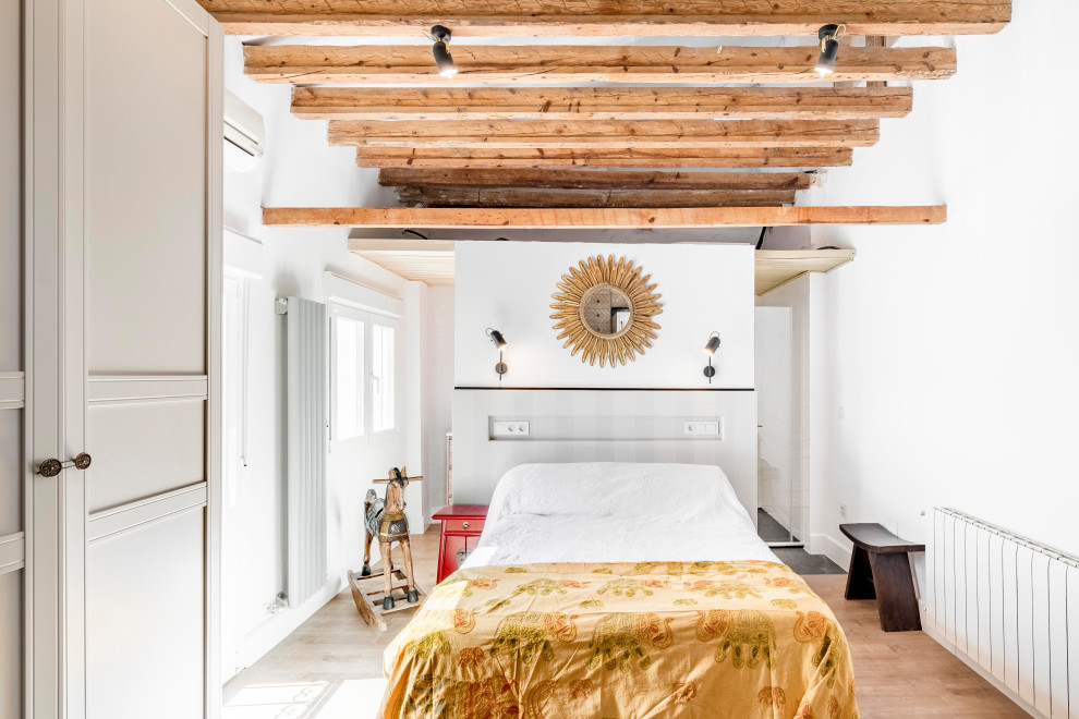 Diseño de dormitorio mediterráneo con paredes blancas, suelo de madera en tonos medios, suelo marrón y vigas vistas