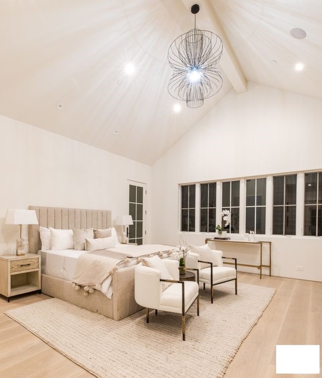 Inspiration for a large contemporary guest bedroom in Los Angeles with white walls, light hardwood flooring, beige floors, a hanging fireplace and a wooden fireplace surround.