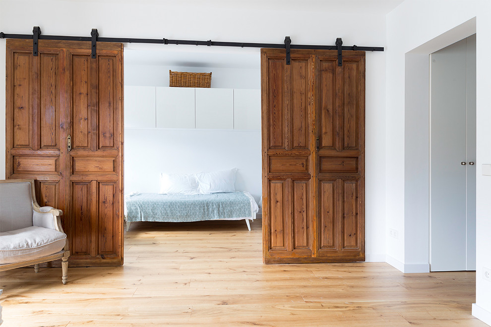 Modelo de dormitorio principal escandinavo de tamaño medio sin chimenea con paredes blancas, suelo de madera clara y suelo beige
