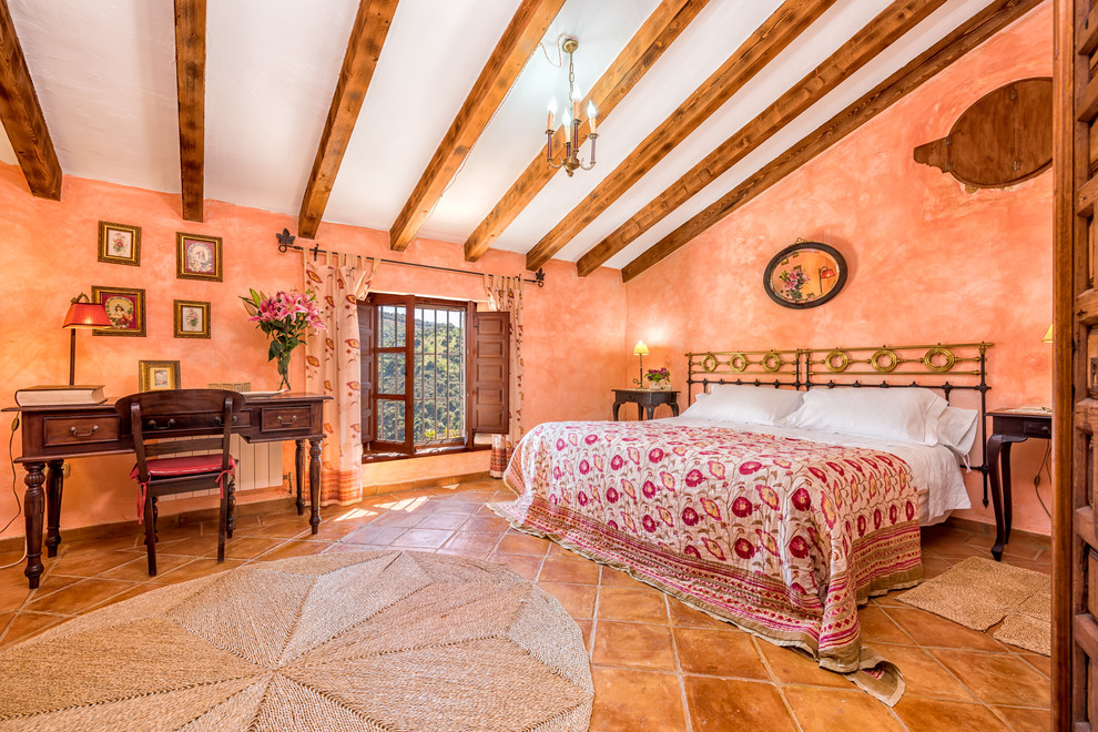 Esempio di una camera matrimoniale mediterranea con pareti arancioni e pavimento marrone