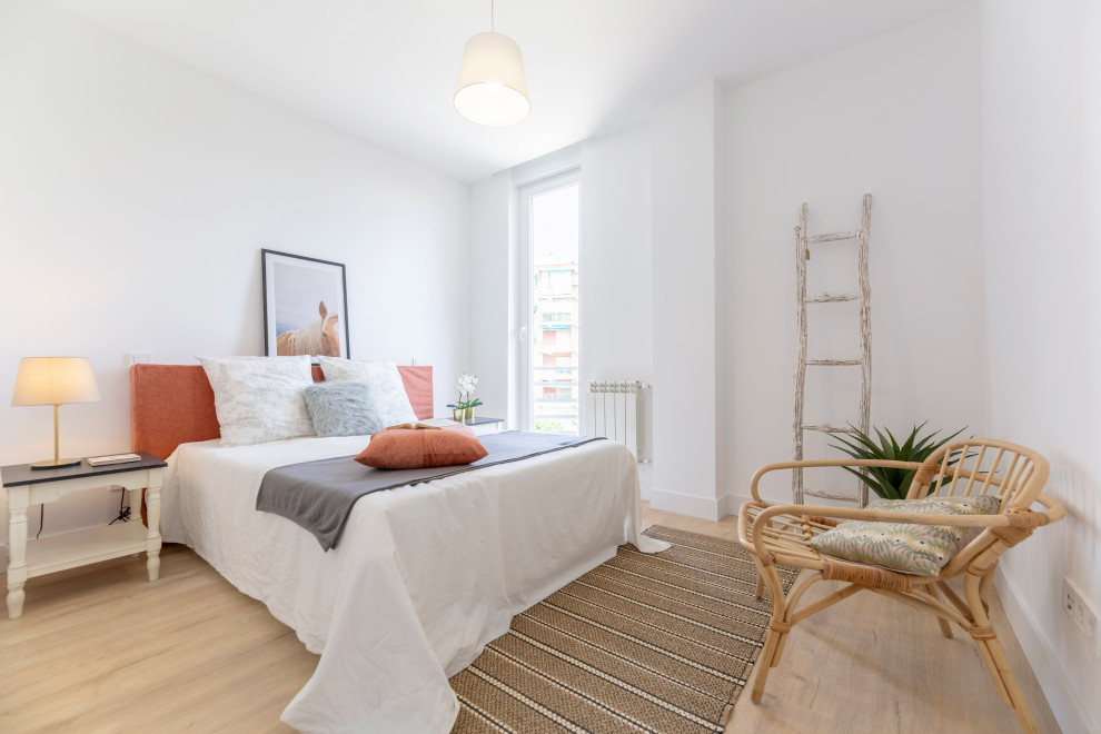Imagen de dormitorio costero con paredes blancas, suelo de madera clara y suelo beige