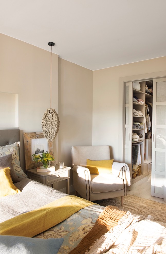 Modelo de dormitorio principal mediterráneo pequeño con paredes beige, suelo de madera clara y suelo beige