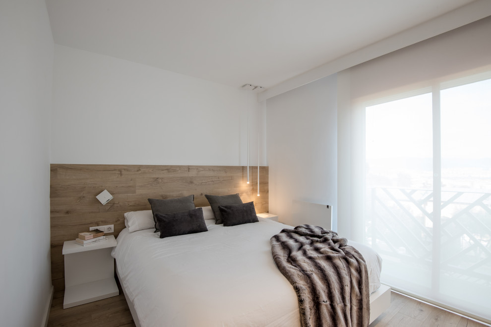 Imagen de dormitorio actual grande con paredes blancas, suelo laminado y suelo marrón