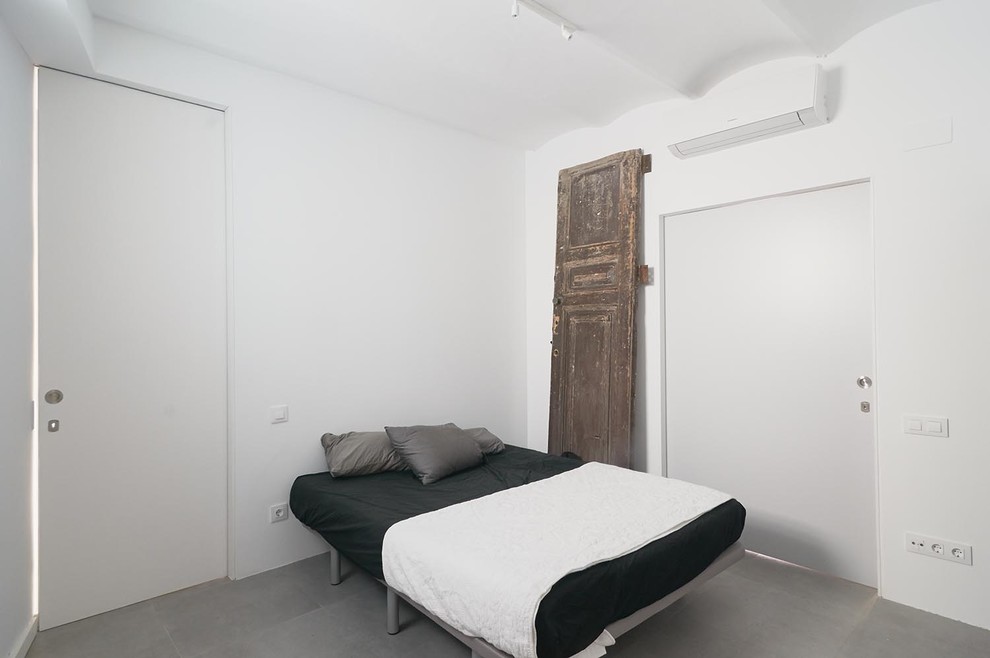 This is an example of a small contemporary master bedroom in Barcelona with white walls, ceramic flooring and no fireplace.