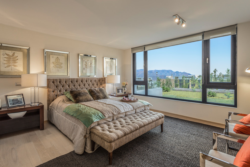 Large contemporary master bedroom in Madrid with medium hardwood flooring, beige walls and beige floors.
