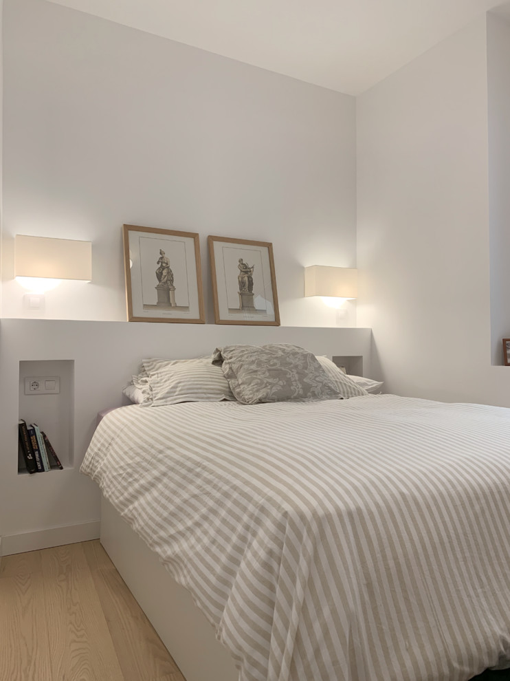 Ejemplo de dormitorio principal y blanco y madera contemporáneo de tamaño medio sin chimenea con paredes blancas, suelo de madera clara y suelo marrón