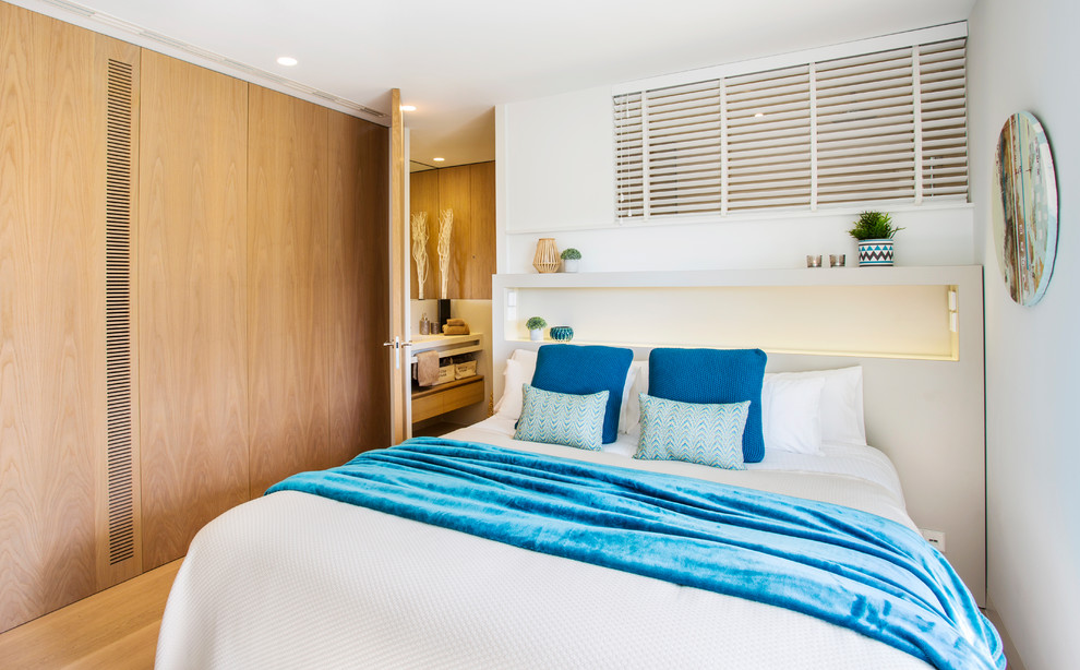 Modelo de dormitorio principal contemporáneo de tamaño medio con paredes blancas, suelo de madera en tonos medios y suelo marrón