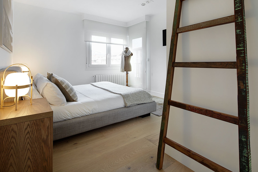 Cette photo montre une chambre parentale tendance de taille moyenne avec un mur blanc, un sol en bois brun et aucune cheminée.