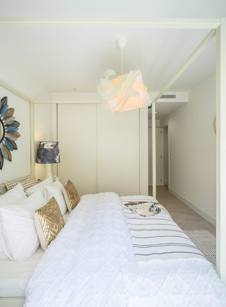 Ejemplo de dormitorio principal tropical de tamaño medio con paredes blancas, suelo de baldosas de cerámica y suelo beige