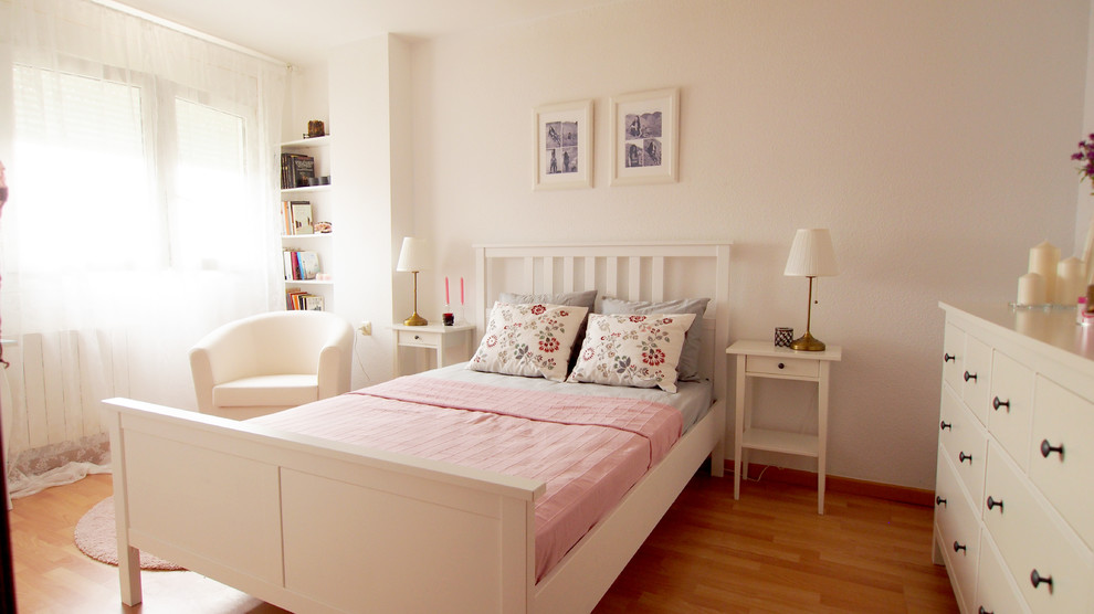 Diseño de dormitorio principal romántico grande con paredes blancas, suelo de madera clara y suelo marrón