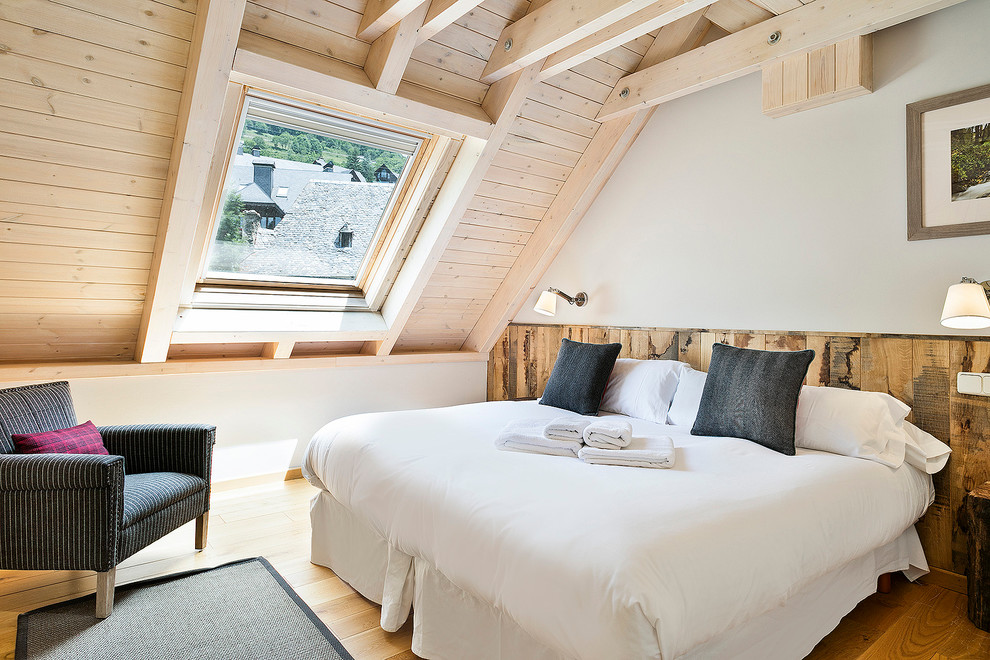 Photo of a medium sized rustic master bedroom in Barcelona with white walls, medium hardwood flooring and no fireplace.