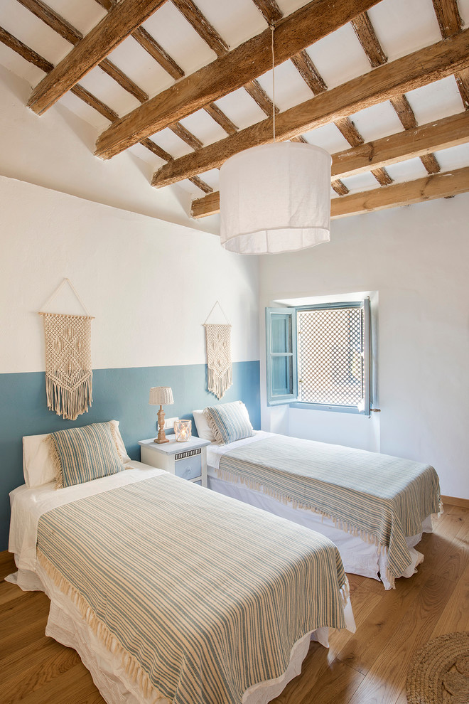 Inspiration pour une chambre d'amis méditerranéenne de taille moyenne avec un mur blanc, un sol en bois brun et un sol marron.
