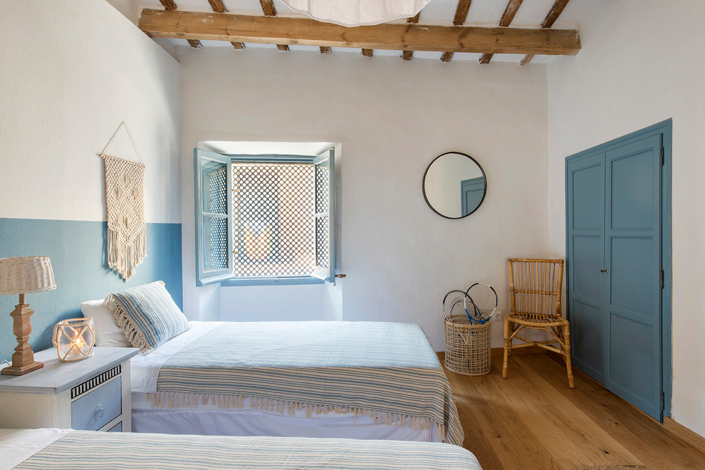 Diseño de habitación de invitados mediterránea de tamaño medio con paredes blancas, suelo de madera en tonos medios y suelo marrón