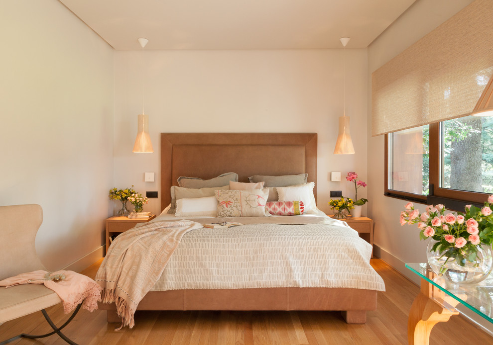 Modelo de dormitorio principal clásico renovado de tamaño medio sin chimenea con paredes blancas, suelo de madera en tonos medios y suelo marrón