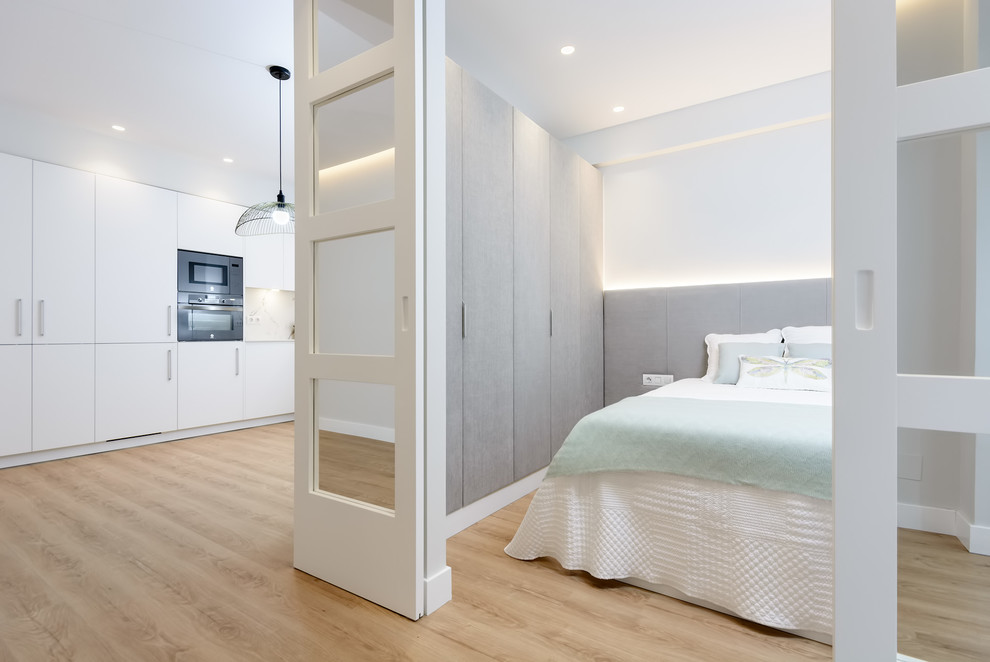 Foto de dormitorio actual sin chimenea con paredes blancas, suelo de madera clara y suelo beige