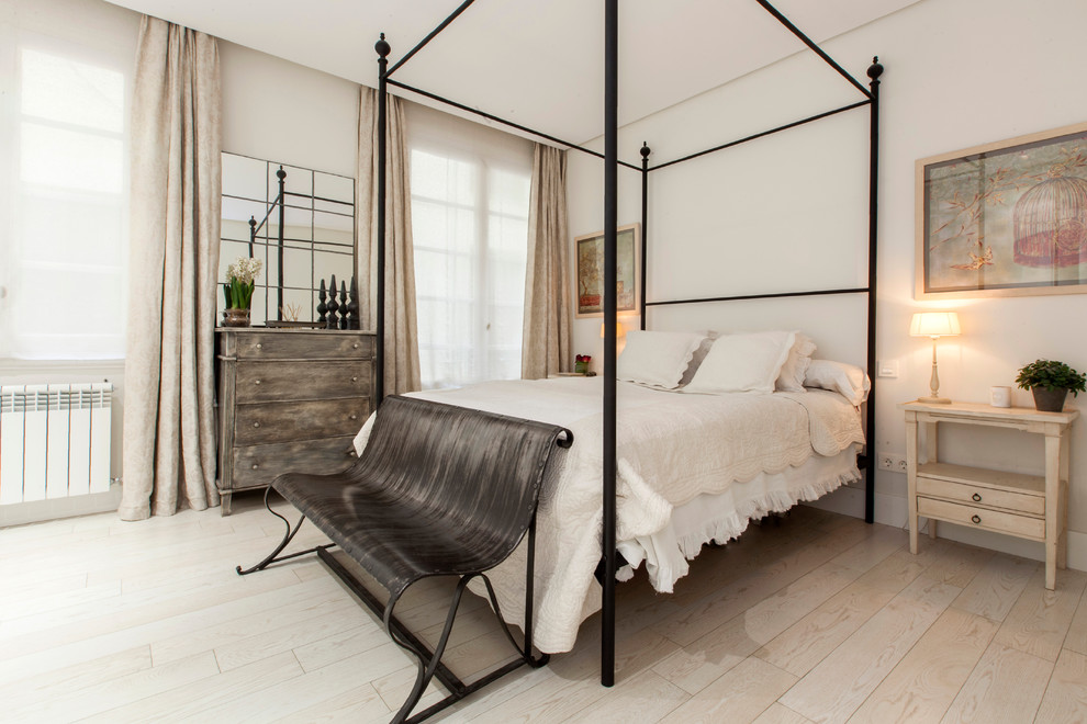 Imagen de dormitorio principal rural de tamaño medio sin chimenea con paredes blancas y suelo de madera clara