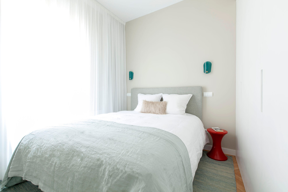 Ejemplo de dormitorio principal actual pequeño sin chimenea con paredes beige y suelo de madera en tonos medios