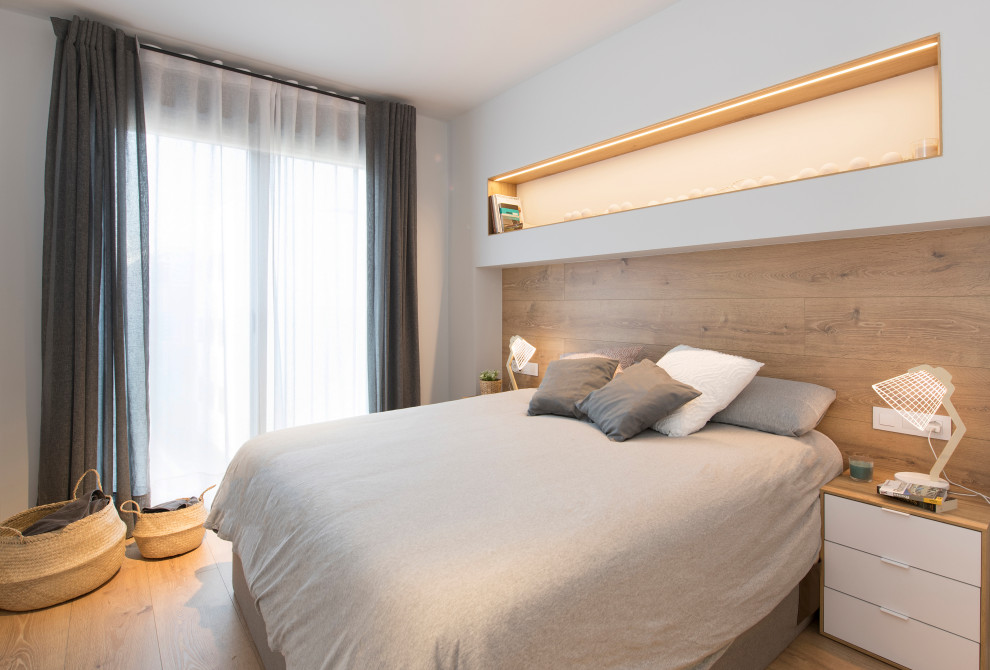 Modelo de dormitorio principal escandinavo de tamaño medio sin chimenea con suelo de madera clara, paredes blancas y suelo beige