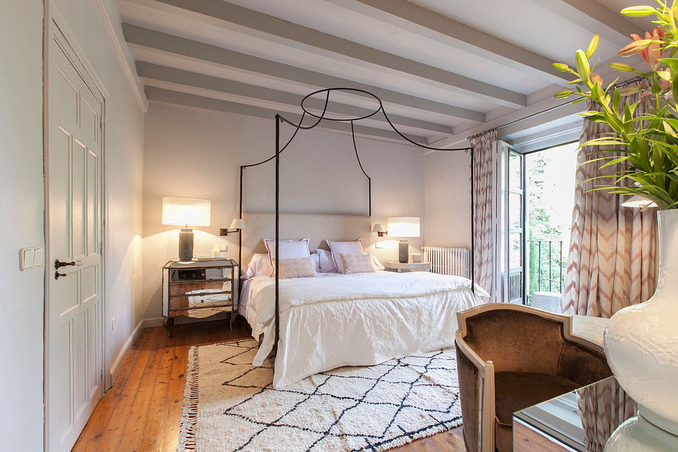 Cette photo montre une chambre parentale chic de taille moyenne avec un mur blanc, un sol en bois brun et aucune cheminée.