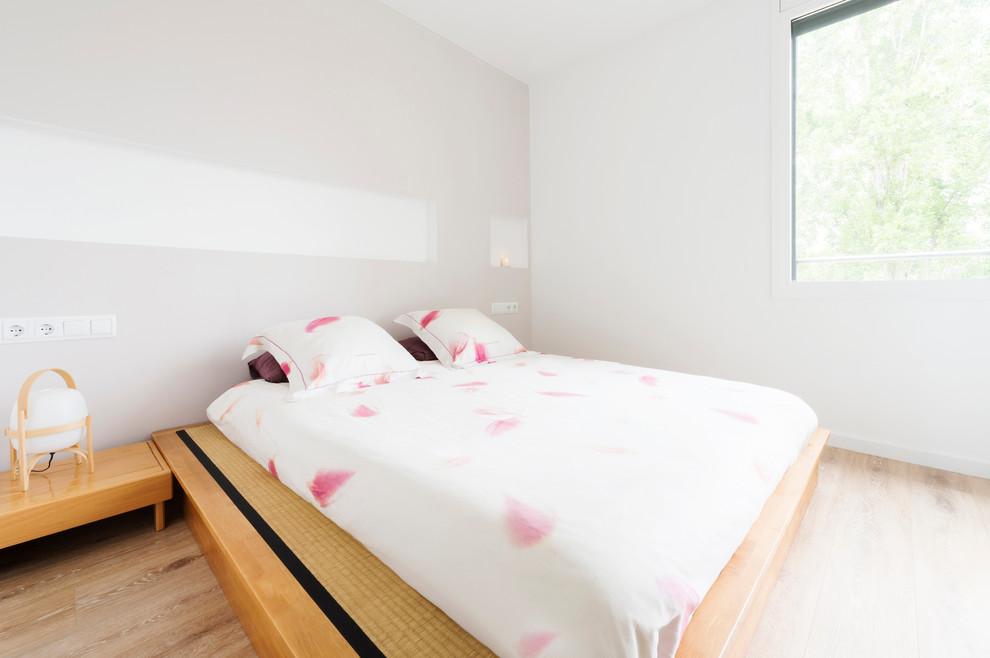 Foto de dormitorio principal nórdico de tamaño medio sin chimenea con paredes blancas y suelo de madera en tonos medios