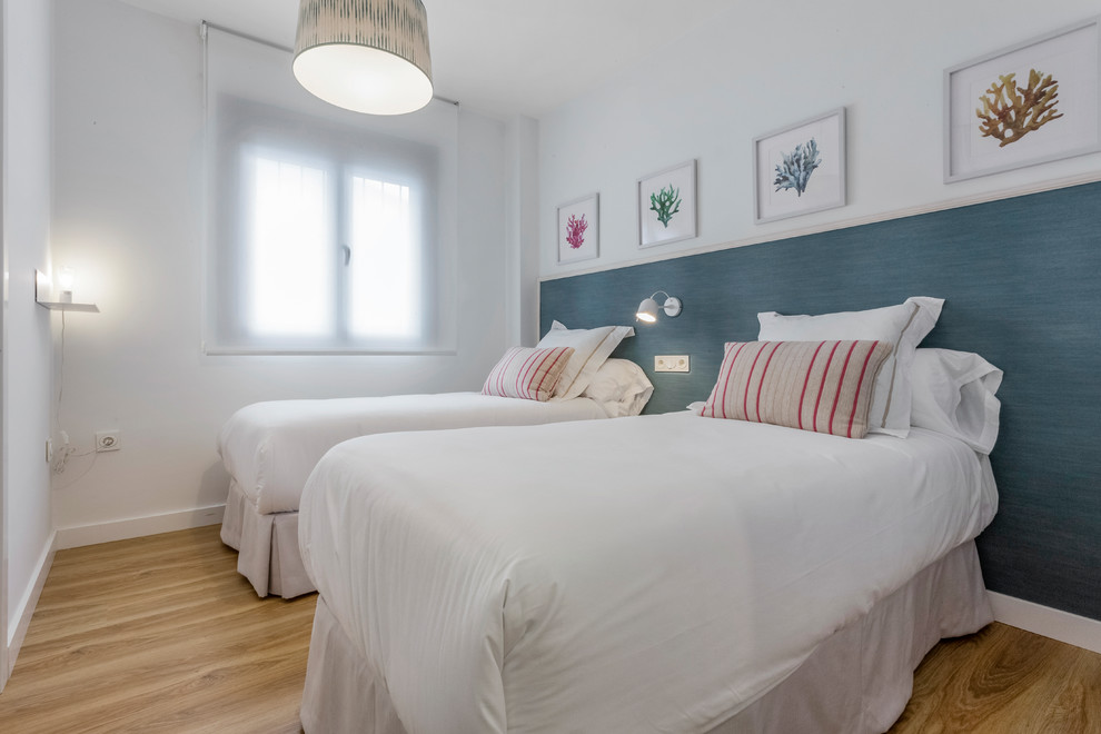 Foto de dormitorio costero con paredes blancas, suelo de madera en tonos medios y suelo marrón