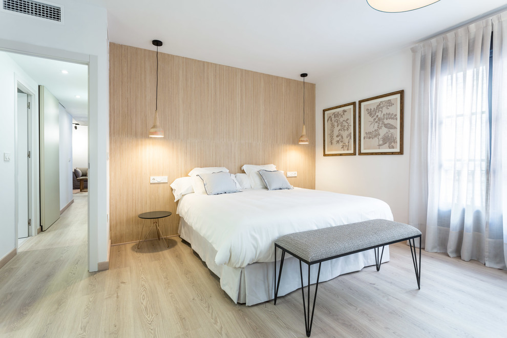 This is an example of a contemporary bedroom in Seville with white walls, light hardwood flooring and beige floors.