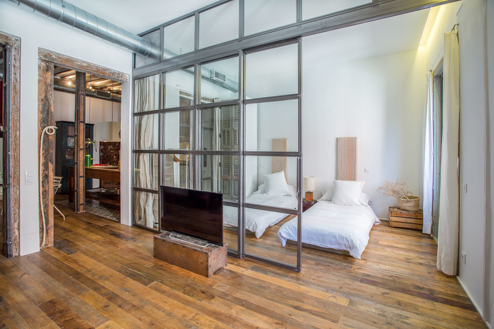 Imagen de habitación de invitados industrial grande sin chimenea con paredes blancas y suelo de madera en tonos medios