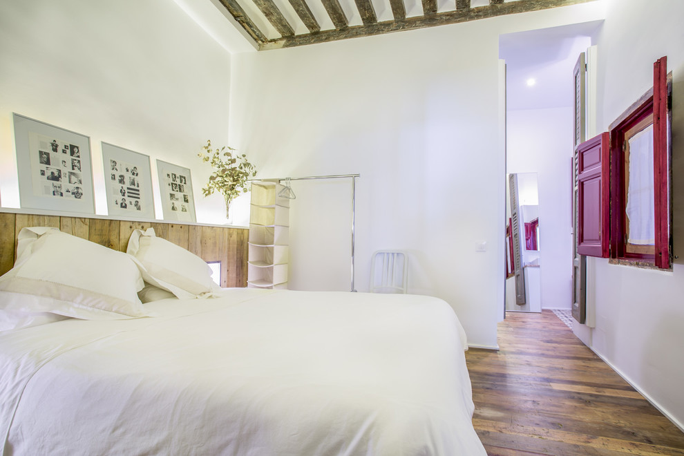 Imagen de dormitorio principal industrial de tamaño medio sin chimenea con paredes blancas y suelo de madera en tonos medios