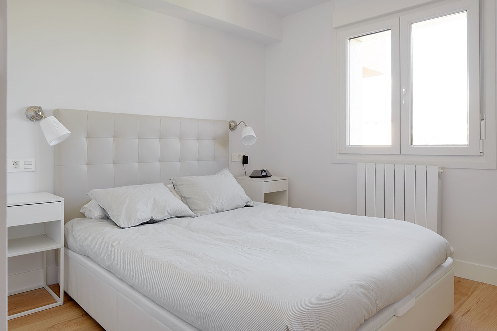 Foto de dormitorio contemporáneo con paredes blancas, suelo de madera en tonos medios y suelo beige