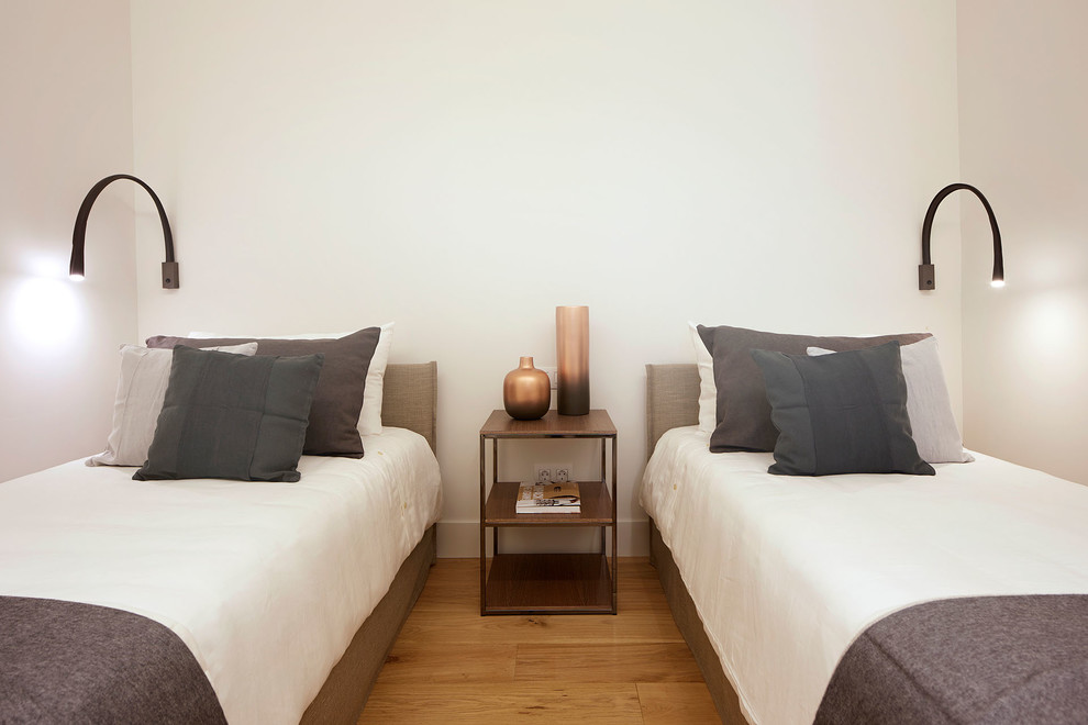 Exemple d'une chambre d'amis tendance de taille moyenne avec un mur blanc, un sol en bois brun et un sol beige.
