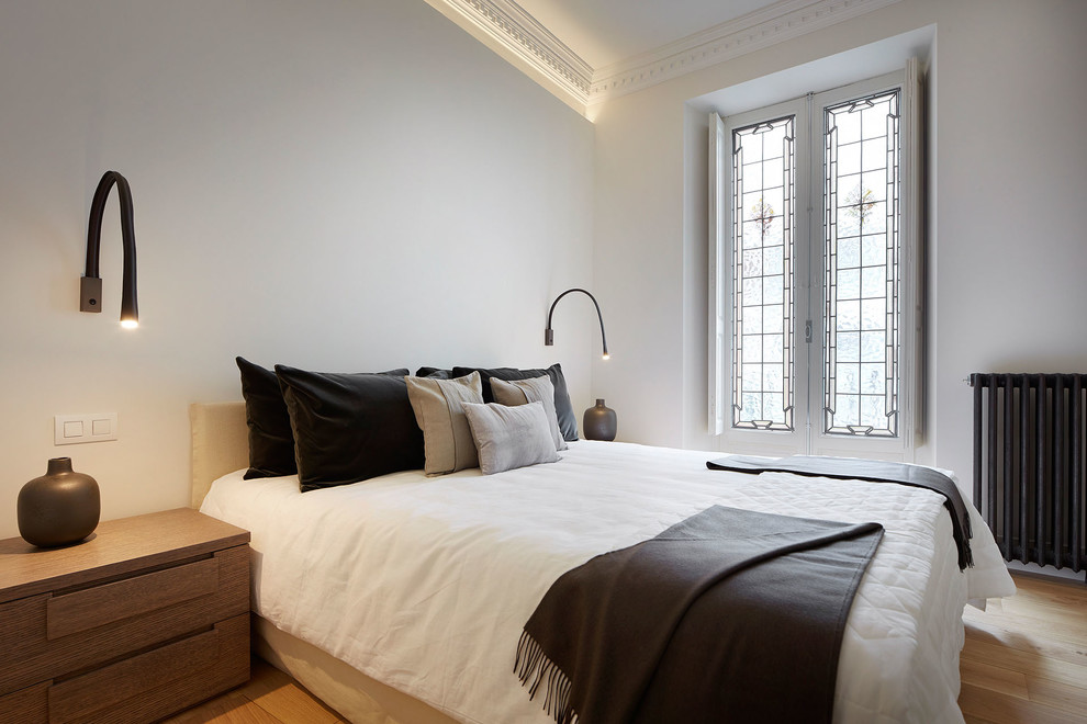 Imagen de dormitorio principal contemporáneo de tamaño medio con paredes blancas, suelo de madera en tonos medios y suelo beige