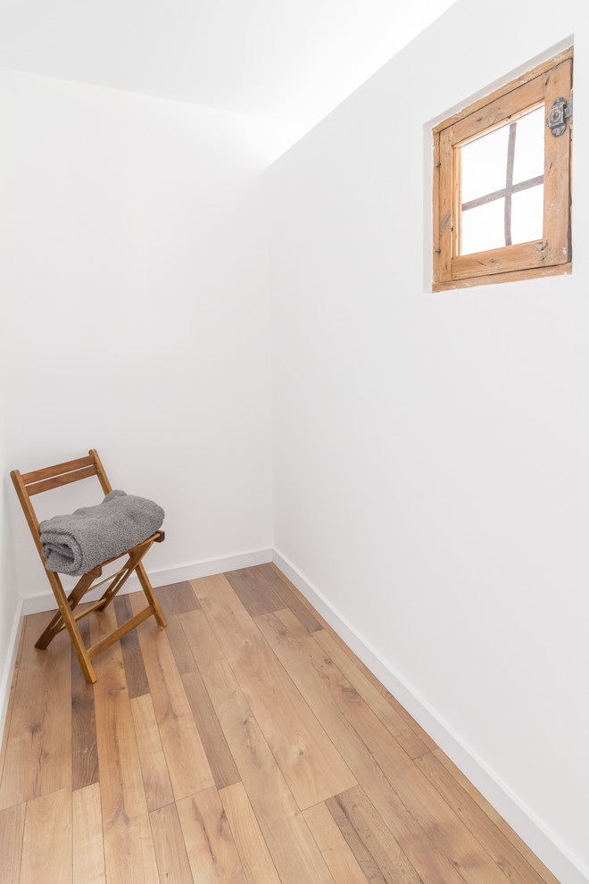 Foto de dormitorio nórdico con paredes blancas, suelo de madera en tonos medios y suelo marrón