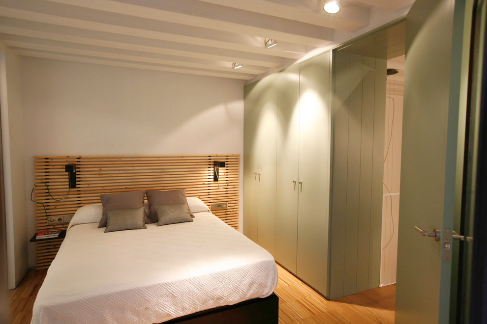 Ejemplo de dormitorio principal moderno de tamaño medio sin chimenea con paredes blancas y suelo de madera en tonos medios